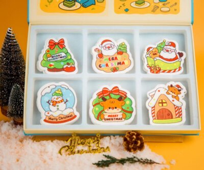 Santa Friends cellulose sponge set displayed with Doyourclean box and holiday decorations on yellow background.
