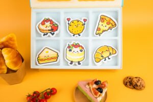 Doyourclean Bakery Friends Collection – 6 Designs, 18 Sponges Bakery Friends eco sponge set displayed with pastries and cookies, featuring all six designs and branded box.