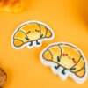 Bakery Friends â Croissant Biodegradable Sponge | Doyourclean Croissant-shaped cellulose sponges from Doyourclean Bakery Friends series on yellow background with bakery props.