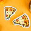 Bakery Friends â Pizza Eco Sponge | Doyourclean Pizza slice-shaped cellulose sponges with melted cheese illustration, photographed on warm yellow surface with cookies and bread decor.