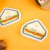Bakery Friends â Sandwich Cellulose Sponge | Doyourclean Sandwich-shaped cellulose sponges from Doyourclean Bakery Friends series on yellow background with cookies and bread decor.