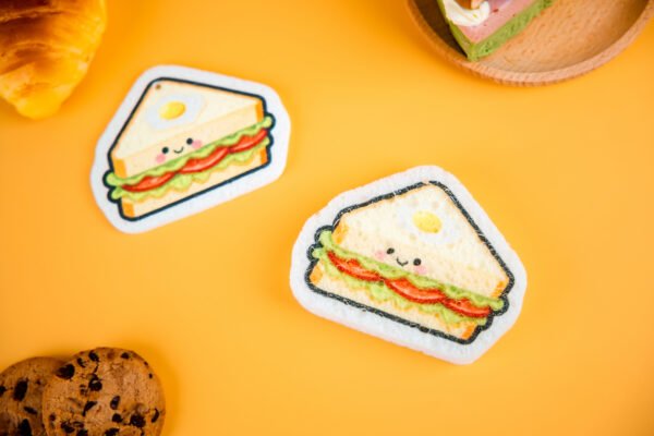 Bakery Friends â Sandwich Cellulose Sponge | Doyourclean Sandwich-shaped cellulose sponges from Doyourclean Bakery Friends series on yellow background with cookies and bread decor.