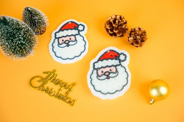 Christmas Friends â Santa Claus Eco Sponge | Doyourclean Santa Claus-shaped cellulose sponges on Christmas setup with pinecones and ornaments.