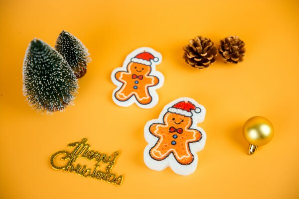 Christmas Friends â Gingerbread Man Biodegradable Sponge | Doyourclean Gingerbread man-shaped cellulose sponge photographed with pine decor and gold ornaments.