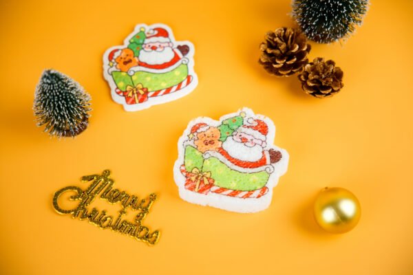 Santa Friends â Santa Sleigh Sponge | Before & After Absorption Display A comparison of two Santa-in-sleigh cellulose sponges from Doyourcleanâs Santa Friends series â one dry and one expanded with water, showing texture and absorption performance.