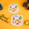 Santa Friends â Santa Claus Biodegradable Sponge | Doyourclean Santa-shaped cellulose sponge from Doyourclean Santa Friends collection on yellow Christmas background with pinecones and ornaments.