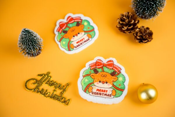 Santa Friends â Reindeer Biodegradable Sponge | Doyourclean Reindeer-shaped cellulose sponge with ribbon design and Christmas ornaments.