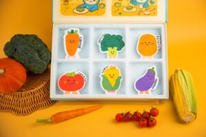 Vegetable Friends Biodegradable Sponge Set | Doyourclean Different angle of Doyourclean Vegetable Friends cellulose sponge box surrounded by vegetables.