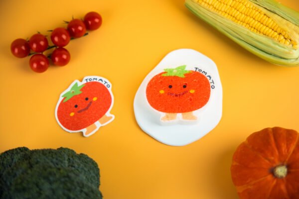 Vegetable Friends â Tomato Biodegradable Sponge | Doyourclean Single tomato-shaped cellulose sponge with a smiling face on a yellow backdrop.