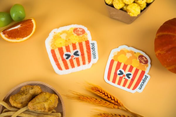 Tasty Friends â Popcorn Sponge | Sustainable Kitchen Essential Two popcorn-bucket cellulose sponges by Doyourclean placed with snacks on yellow background.