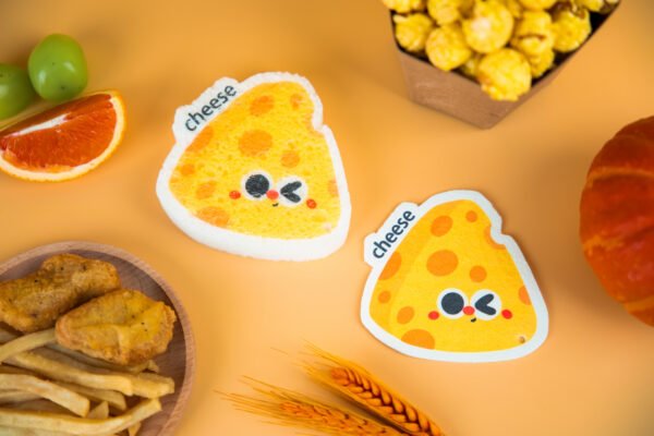 Tasty Friends â Cheese Sponge | Cute Kitchen Cleaning Gift Two cheese-shaped Doyourclean eco sponges with yellow texture and cartoon eyes.
