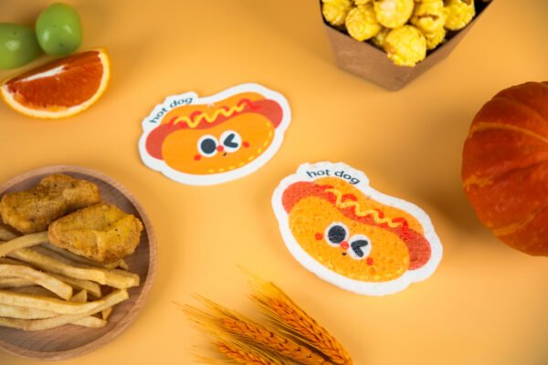 Tasty Friends â Hotdog Sponge | Biodegradable Cellulose Two Doyourclean hotdog sponges on golden surface with wheat and pumpkin decor.