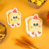 Tasty Friends â Toast Sponge | Doyourclean Eco Collection Two toast-shaped Doyourclean cellulose sponges with smiling faces, surrounded by snacks on yellow background.