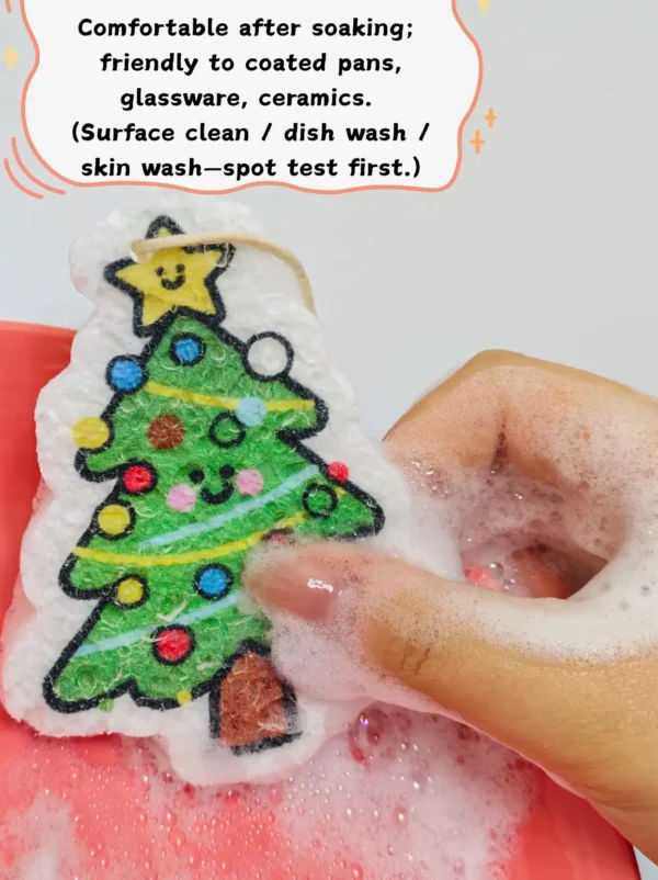 Christmas tree cellulose sponge being used to wash a dish on a red plate with foam and water.