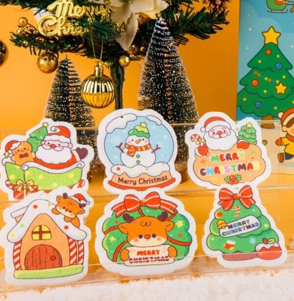 Santa Friends â Christmas Gift Sponge Box | Eco Holiday Cleaning Set A set of Doyourclean Santa Friends cellulose sponges featuring Santa, reindeer, sleigh, and candy house, arranged with Christmas decorations and snow props.