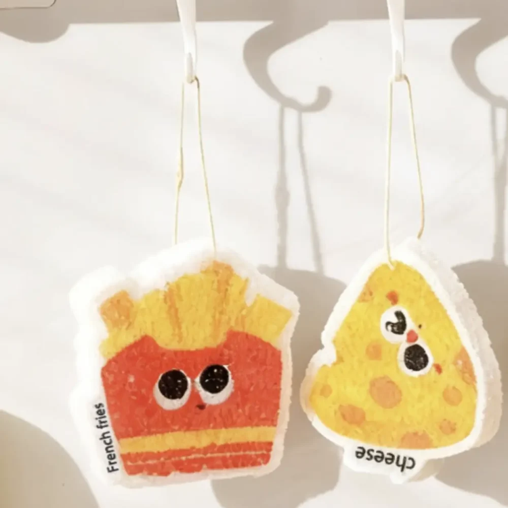 French fries and cheese cellulose sponges hanging by cords to dry